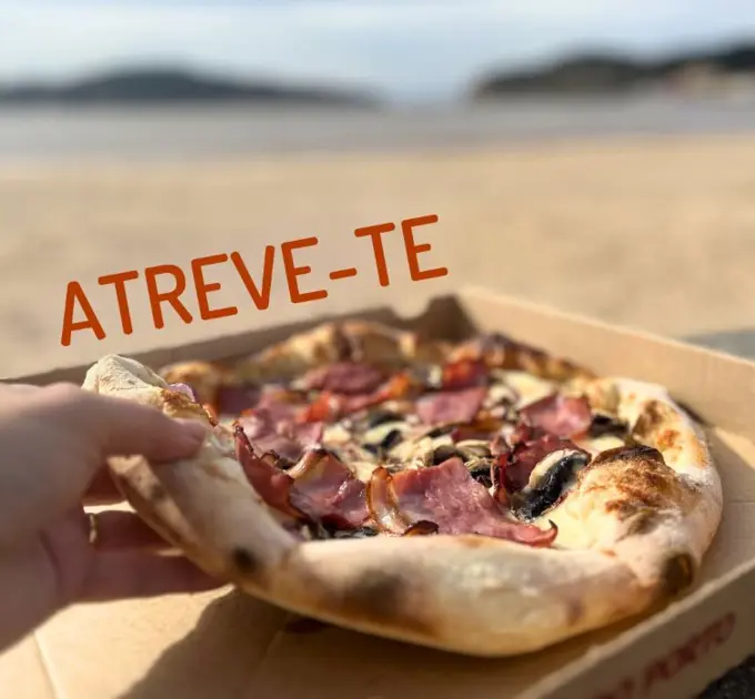 Uma pizza na caixa segurada em frente à baía de São Martinho do Porto