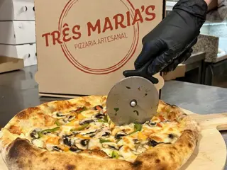 Uma pizza a ser cortada com o cortador, a caixa da casa atrás
