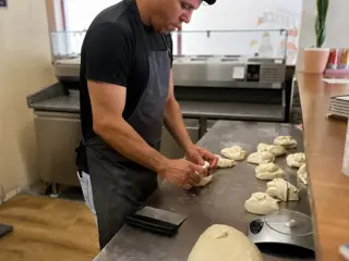 Um pizzaiolo a dividir a massa na bancada da cozinha