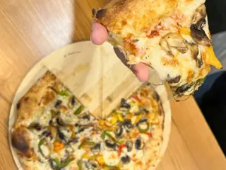 Uma fatia levantada de uma pizza de cogumelos e pimentos