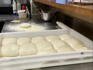 Bolas de massa num tabuleiro branco, prontas a levedar