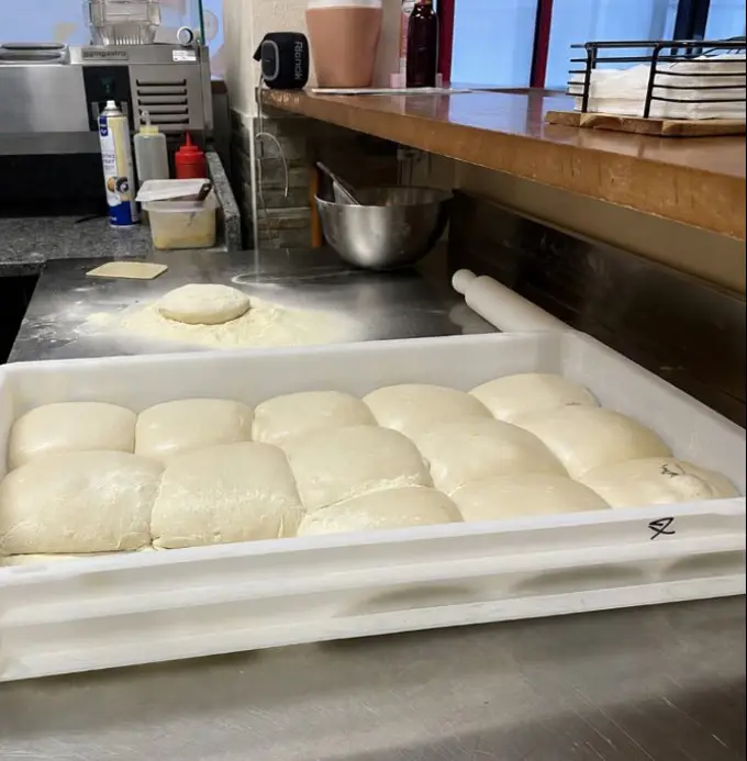 Bolas de massa num tabuleiro branco, prontas a levedar
